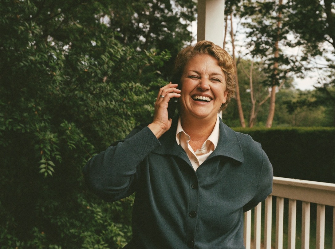 A woman laughing on the phone on her front porch